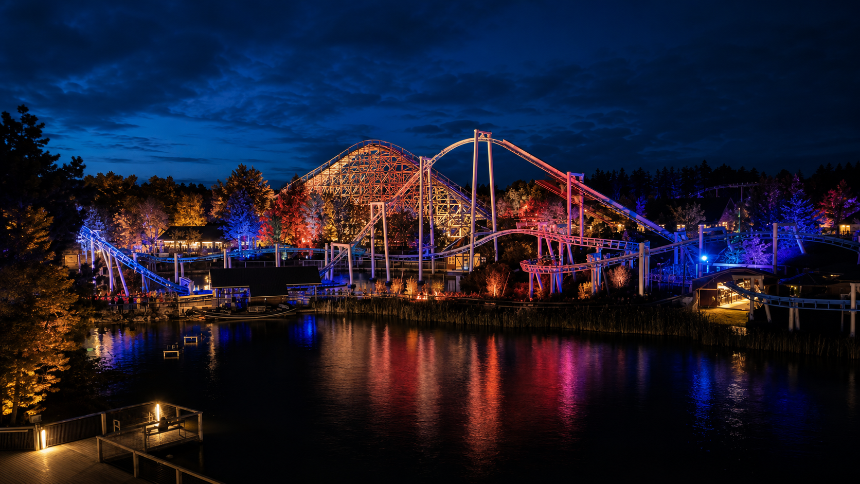 Theme park roller coasters illuminated with blue, pink and amber lighting at night